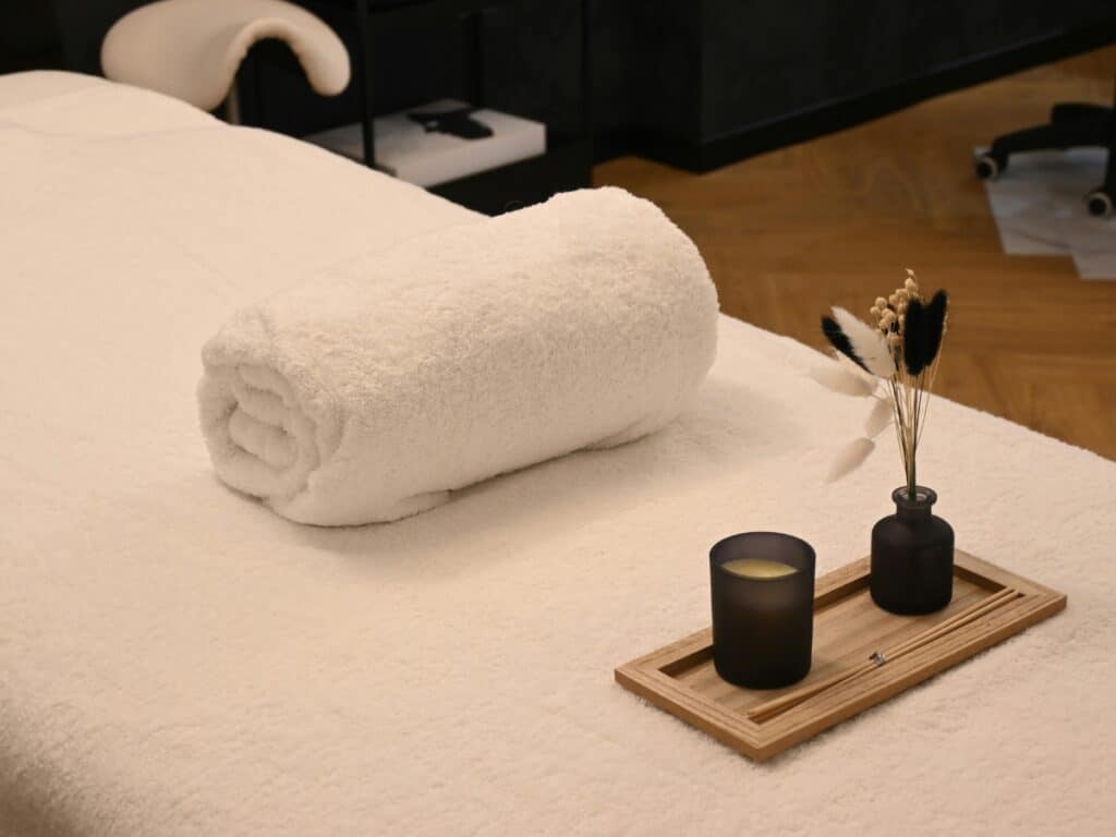 Cabine de soin épurée et lumineuse du centre esthétique eliskin à Bordeaux, table de traitement avec serviette blanche et diffuseur